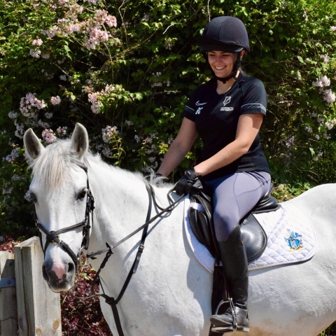 Student riding a white horse